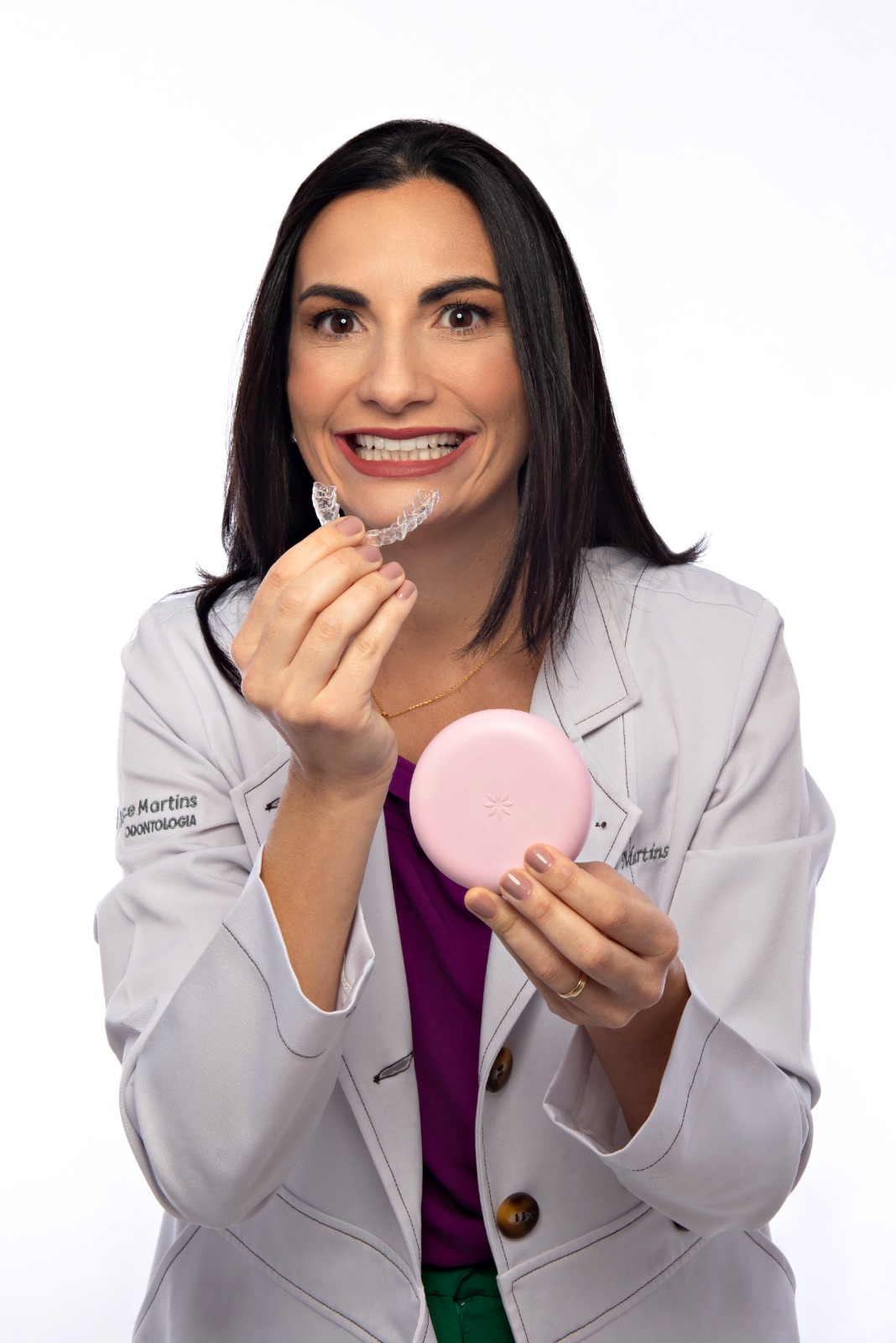 Dra. Joyce Martins segurando um alinhador invisível Invisalign